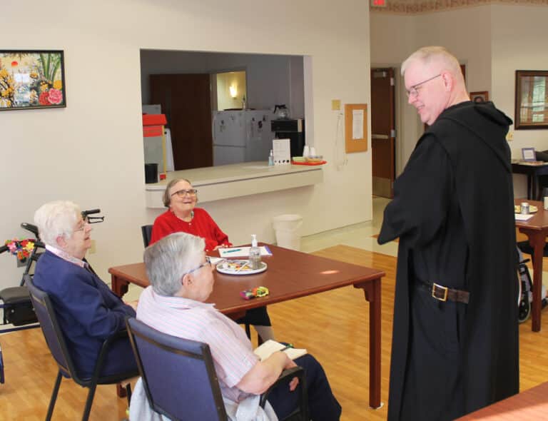 Father Godfrey Mullen jokes that “this table looks like trouble” as he converses prior his afternoon session with Sister Eva Boone (in blue), Sister Lois Lindle (in red) and Sister Ruth Gehres.