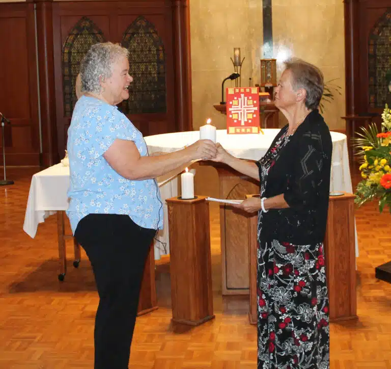 Sister Martha Keller, left, passes a candle to her longtime friend Sister Alicia Coomes, the new assistant congregational leader. Sister Martha Keller, left, passes a candle to her longtime friend Sister Alicia Coomes, the new assistant congregational leader.