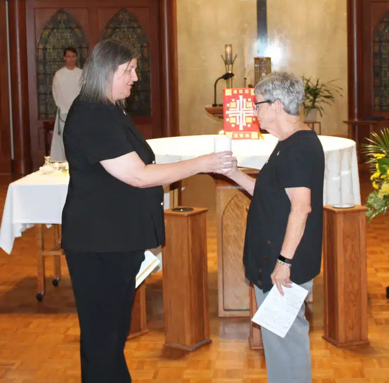 Sister Monica Seaton, left, passes her candle to Sister Judith Nell Riney, a new councilor. Sister Monica Seaton, left, passes her candle to Sister Judith Nell Riney, a new councilor.