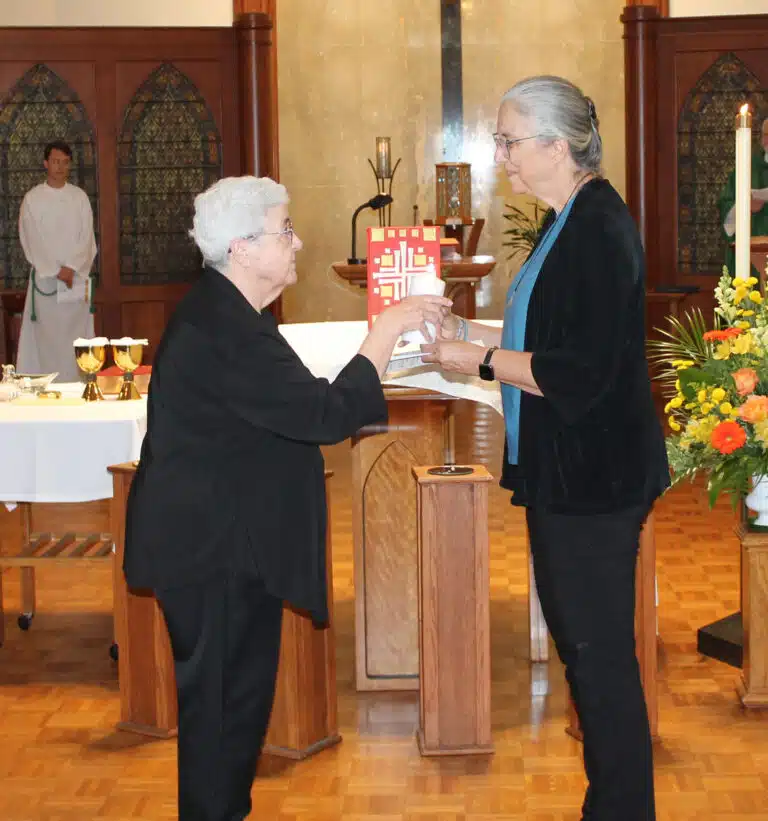 Sister Ann McGrew, left, passes her candle to Sister Larraine Lauter, a new councilor. Sister Ann McGrew, left, passes her candle to Sister Larraine Lauter, a new councilor.