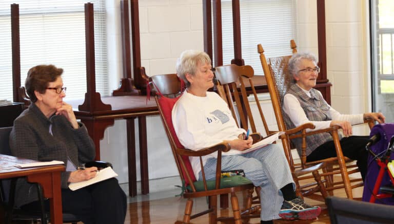 We have the Franciscans to thank for making the stable where Jesus was born seem nicer than it was, Father Mullen said. “God always deals with the muck,” he said. Listening to his talk are, from left, Sisters Mary Henning, Pam Mueller and Ann Patrice Cecil.