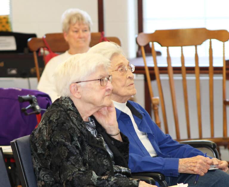 Sister George Mary Hagan, left, and Sister Elaine Burke listen to Father Mullen quote from the Rule of Saint Benedict that we should do whatever we do, “so that in all things, God may be glorified.”