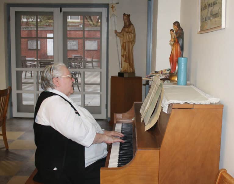 Sister Catherine Marie Lauterwasser entertains the crowd by playing the piano while singing a couple of Irish ballads. Sister Catherine Marie has often served as the cantor for Mass at Maple Mount.