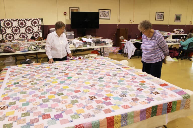 Sister Amelia Stenger, left, and her sister, Ursuline Associate Mary Teder, look over a quilt top completed by Elizabeth Fitzgerald and Mary Ruth Clark. It’s made of 30s fabric, a reproduction of feed sacks, Sister Amelia said.