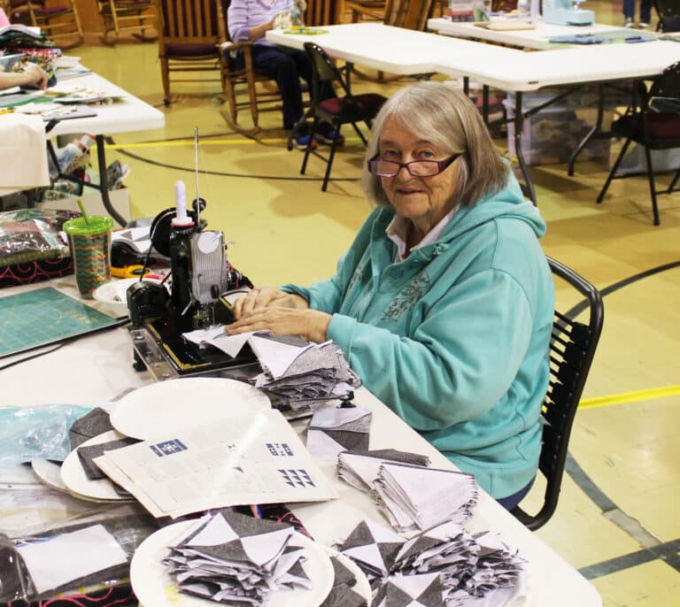 Laura Merz, of Aurora, Ky., cuts small black and white squares for her next project.