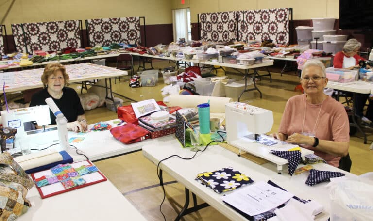 Jean Person, left, of Fayette County, Tenn., and Beverly Howell, of Covington, Tenn., work on their projects in Maple Hall. In the background are tables full of donated fabric that the Quilting Friends can use.