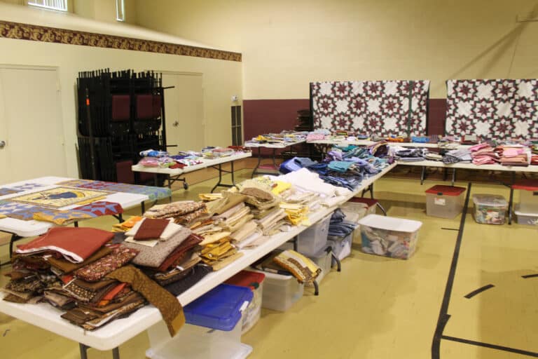 Sister Amelia works in advance to sort the donated fabric by color for the Quilting Friends to choose.