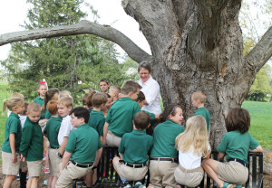 Sister Amelia smiles as the children gather around the “grandfather” tree on campus. She told them the tree has been at Maple Mount since at least 1898, because it appears in a picture taken when the Guest House was being built that year.
