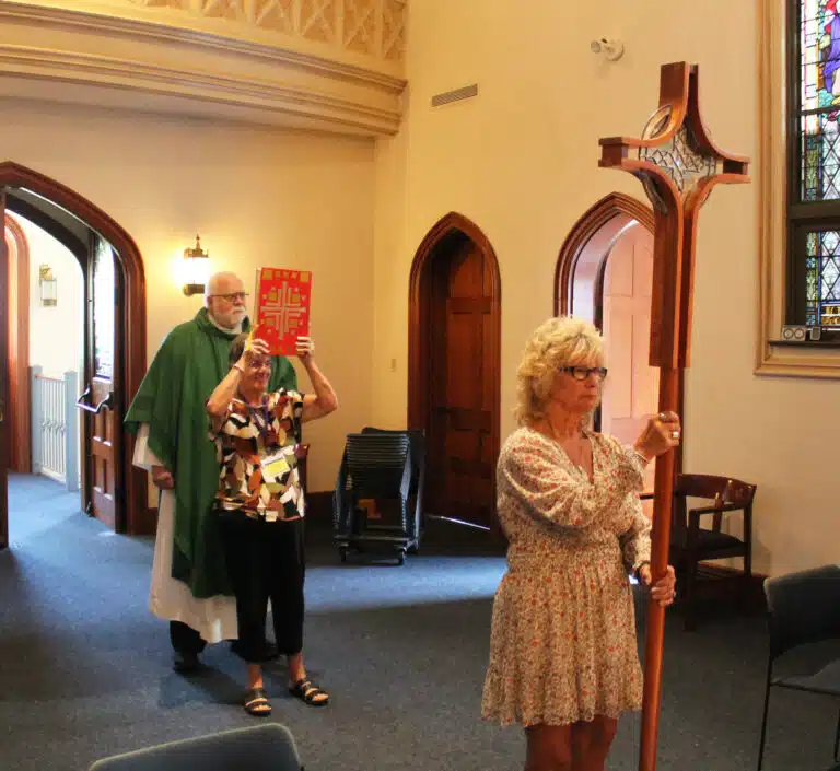 Mary-Anne Causey Powers A’75, prepares to carry the processional cross, as Becky Collins Morris A’71, and Father Ray Goetz follow to begin Mass. Mary-Anne Causey Powers A’75, prepares to carry the processional cross, as Becky Collins Morris A’71, and Father Ray Goetz follow to begin Mass.