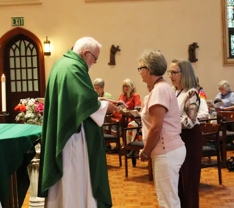 Jane Powers Thomas, left, and Renee Mayhew Shoemaker, both of the class of 1976, deliver the offertory gifts to Father Ray Goetz. Jane Powers Thomas, left, and Renee Mayhew Shoemaker, both of the class of 1976, deliver the offertory gifts to Father Ray Goetz.