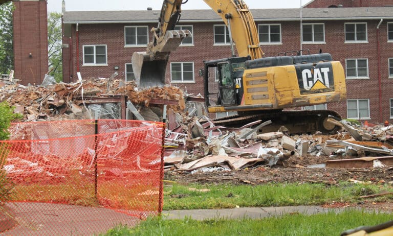 An excavator loosens some of the steel beams still left from the façade of the Retreat Center.