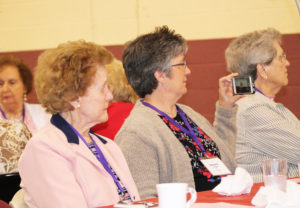 Patricia Sherron Ringswald, A’44, left, listens to her sister read her nomination for the Maple Leaf Award as her niece Melanie Phipps records the moment with her phone. Dorothy Payne Krumpelman, A’46, right, the 2010 Maple Leaf Award winner, looks on.