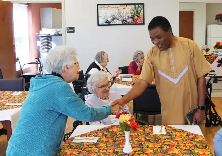 Sister Nancy Murphy welcomes Father John Okoro, as Sister Ann Patrice Cecil looks on. Father John was attending Father Ray Goetz’s farewell party as chaplain. Sister Nancy Murphy welcomes Father John Okoro, as Sister Ann Patrice Cecil looks on. Father John was attending Father Ray Goetz’s farewell party as chaplain.