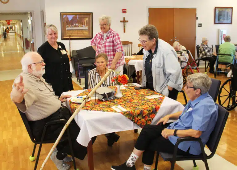 Father Ray is always at home telling a story. Here he is entertaining, from left, long-time nurse Barbara Ervin, Sister Alicia Coomes (seated), Sister Michele Morek, Sister Sharon Sullivan, and Sister Judith Nell Riney.