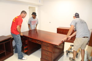 Movers place the desk where it belongs in the Ursuline Partnerships office, where Marian Bennett will work. The offices face north and south.
