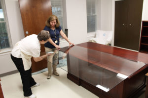 Jennifer Kaminski, right, who works in the Communications office, steadies the glass going on a desk as Sister Amelia Stenger cleans it on May 26.