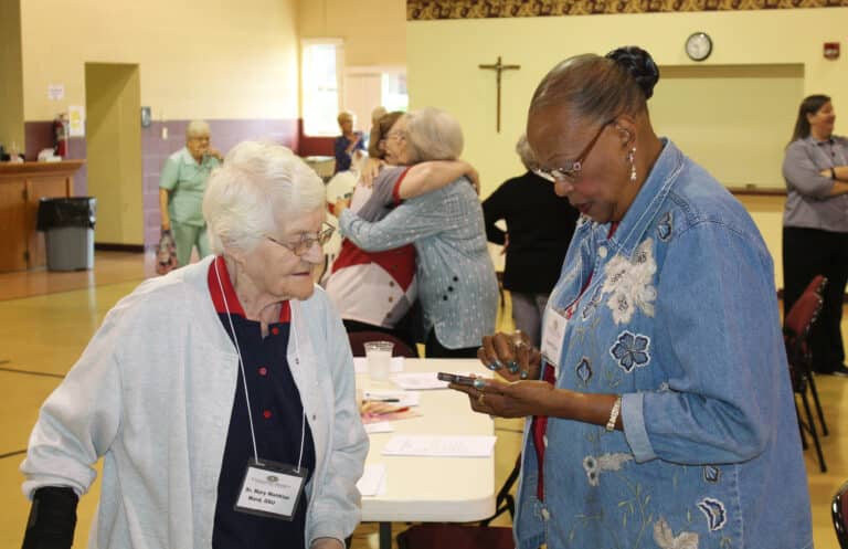 Sister Mary Matthias Ward, left, awaits whatever Lewisport, Ky., Associate Joanne Mason was looking for on her phone.