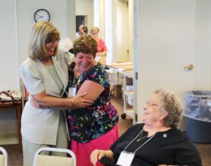 Associate Rise Karr, left, hugs Associate Joan Perry as they share a laugh with Associate Jean Simpson, right. All three are members of the Associate Advisory Board who helped plan the day.