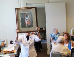 Sister Nancy Murphy is partly hidden by the picture she is carrying of Jesus knocking on the door, inspired by Revelation 3:20: “Behold, I stand at the door and knock. If any man hears my voice, and open the door, I will come in to him.” The picture was the impetus for “Opening Doors of Mercy.”