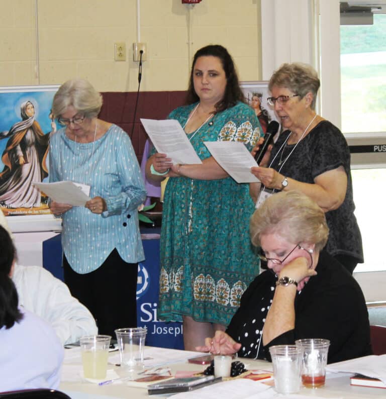 Sister Betsy Moyer, right, reads her part of the prayer honoring those Associates celebrating significant anniversaries this year, as Associates Renee Schultz and Pauline Goebel follow along.