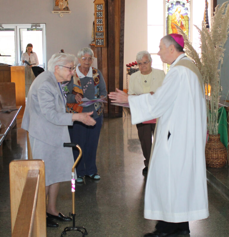 Bishop William Medley welcomes Sister George Mary Hagan on her 70th jubilee. In the background, Ursuline Sisters Mary Celine Weidenbenner, left, and Cecelia Joseph Olinger, bring Sister George Mary her gifts. Bishop William Medley welcomes Sister George Mary Hagan on her 70th jubilee. In the background, Ursuline Sisters Mary Celine Weidenbenner, left, and Cecelia Joseph Olinger, bring Sister George Mary her gifts.