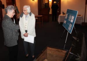 Sister Nancy Murphy, left, visits with Magdalen Kaelin as they look over some of Father Volk’s artifacts, including his trunk that contains his hat.