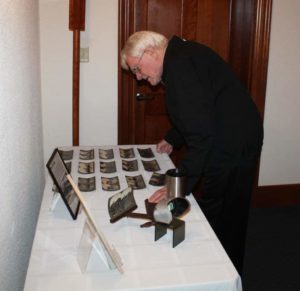 Father Richard Powers looks over some photos on display from the Father Volk collection.