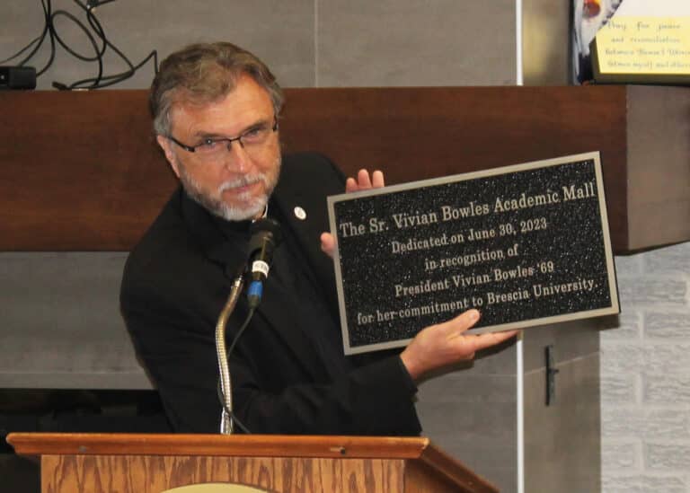 Father Larry Hostetter, who succeeded Sister Vivian as Brescia president in 2007, holds the plaque that will be placed in the Academic Mall.