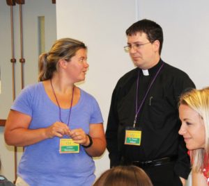 Crissy Stevenson, one of the co-leaders of CLI, talks with Father Daniel Dillard as the students work on their puzzles.