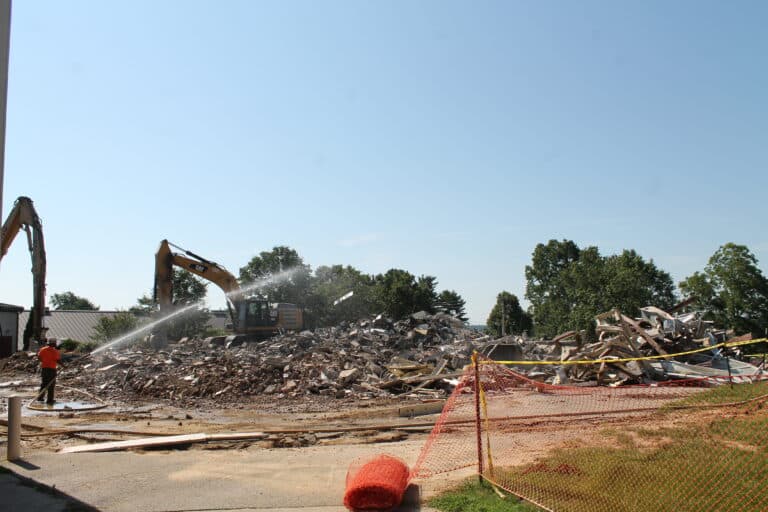 A contractor sprays water to keep the dust down about 9:30 a.m. on July 12, 2023, as Paul Volk Hall was reduced to rubble.