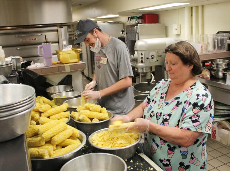 All the corn shucking and cutting was completed on the morning of Aug. 1, but there was plenty of processing to do. Here, Food Service staff Cody Cravens and Charlotte Stelmach cut corn off the cob to prepare for freezing.