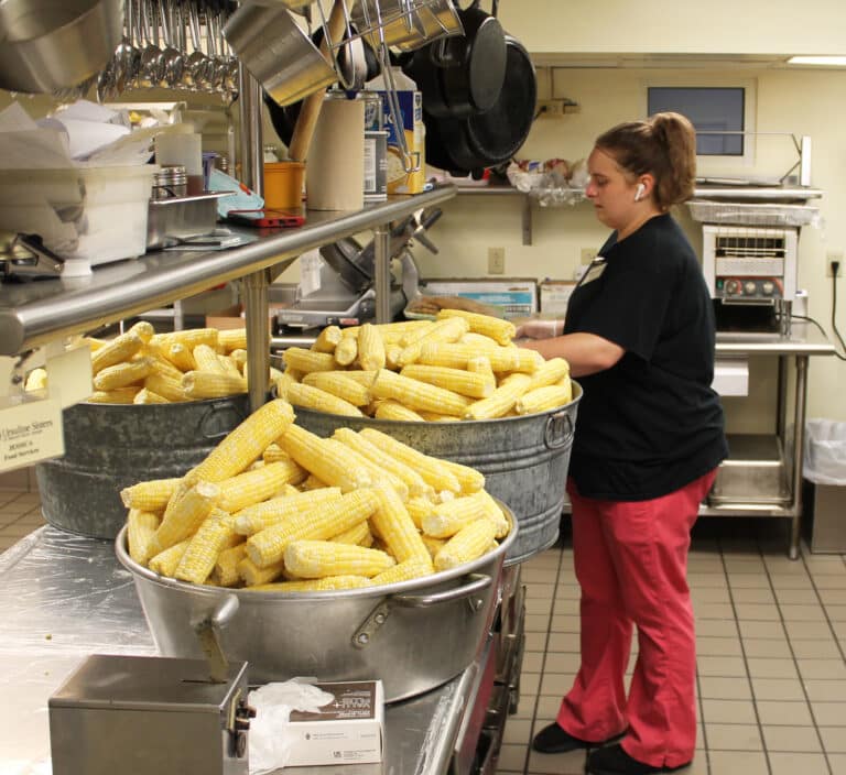 Food Service staff member Amanda Geary works among the corn-ucopia of the kitchen on Aug. 1.