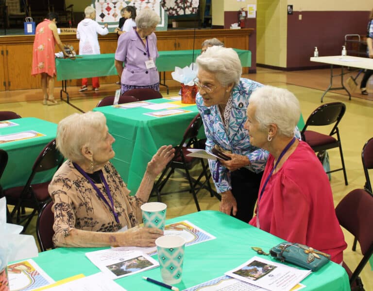 Sister Elaine Burke, A’49, standing, and Kathy Ford Young A’70, right, talk with Delores 