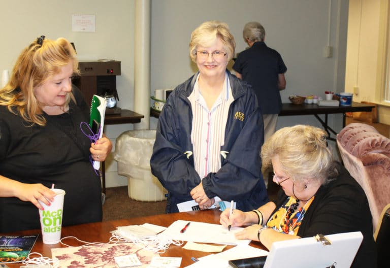 New Ursuline Associate Lori Haynes, of Whitesville, Ky., left, gives her name to Ursuline Associate Suzanne Reiss during registration, as Owensboro Associate Susie Westerfield looks on
