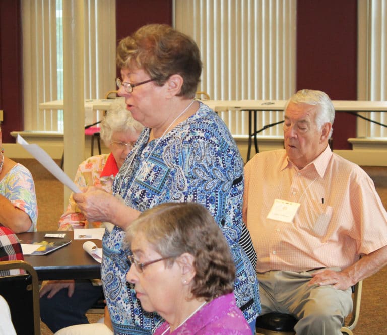 Ursuline Associate Joan Perry reads the opening prayer, as Associate Mike Sullivan and others read along.
