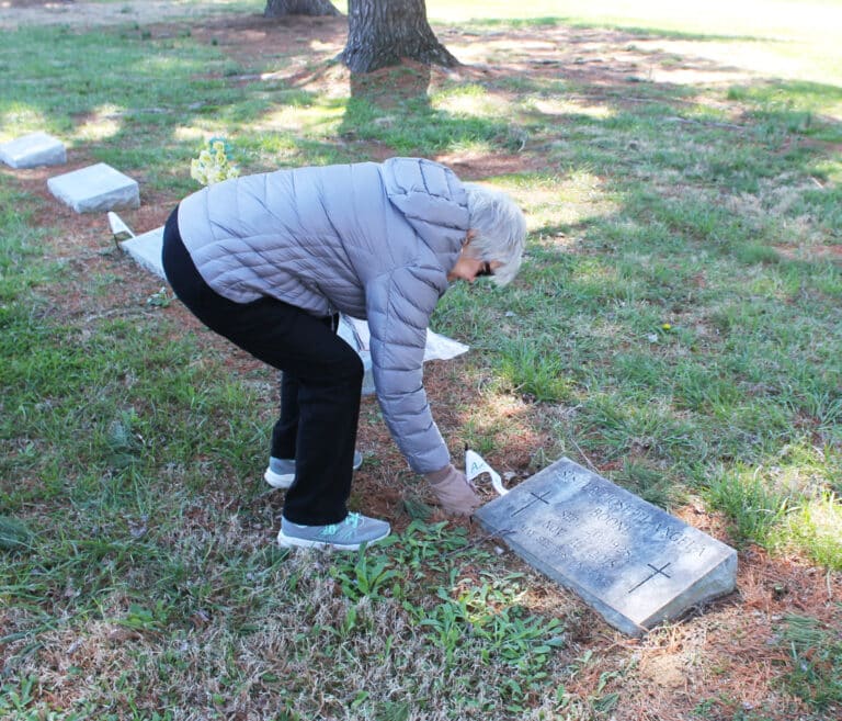 Judy Adams places a flag on the grave of Sister Joseph  Angela Boone. Among her many accomplishments, Sister Joseph Angela was one of the few women in the country to be named chancellor of a diocese, which she did for the Diocese of Owensboro.