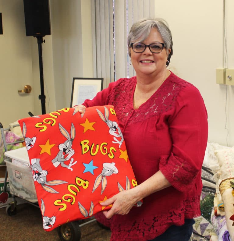 Jo Anna Pearson, of Columbus, Ga., holds a “quillow” – a quilt that folds into a pillow – that she made with fabric donated for the Quilting Friends.
