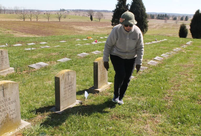 Edna Murphey places a flag on the grave of Sister Joan Marie Lechner, the first resident president of Brescia College in Owensboro.