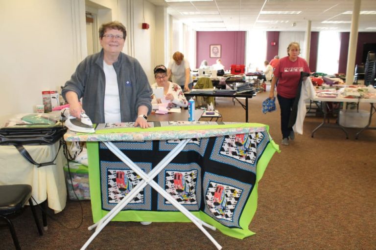 Congregational Leader Sister Amelia Stenger irons a quilt with fabric featuring stock cars that will end up with some lucky NASCAR fan.