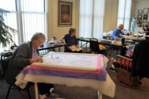 Ursuline Associate Mary Teder does delicate embroidery work on a flowered quilt.