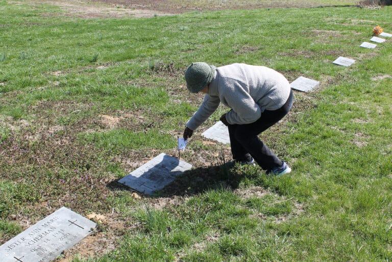 Edna Murphey places a flag on the grave of Sister Marita Greenwell, who took over the Contemporary Woman Program at Brescia College and led it from 1973-2005.