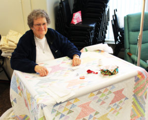Ursuline Associate Mary Teder works on the quilt that will be raffled off as one of the grand prizes at the 46th Mount Saint Joseph Picnic on Sept. 11. It’s called “Flowers in My Basket.” She is Sister Amelia’s sister. Teder’s daughters and granddaughter were helping with aprons and other items.