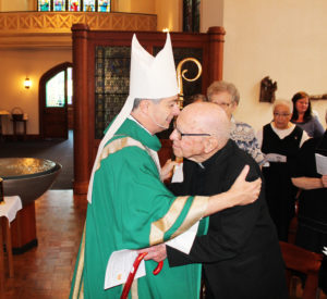 Bishop William Medley stops during his entrance into the Motherhouse Chapel to embrace Father Joseph “Doc” Lyon, a retired priest in the Archdiocese of Louisville.