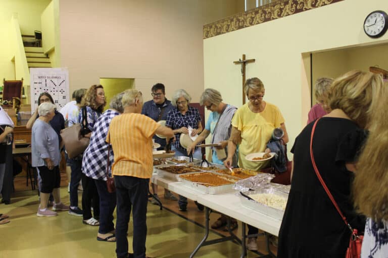 Attendees enjoy getting a plate of pulled pork, baked beans, potato salad, rolls, cornbread, cookies, and drinks for lunch.