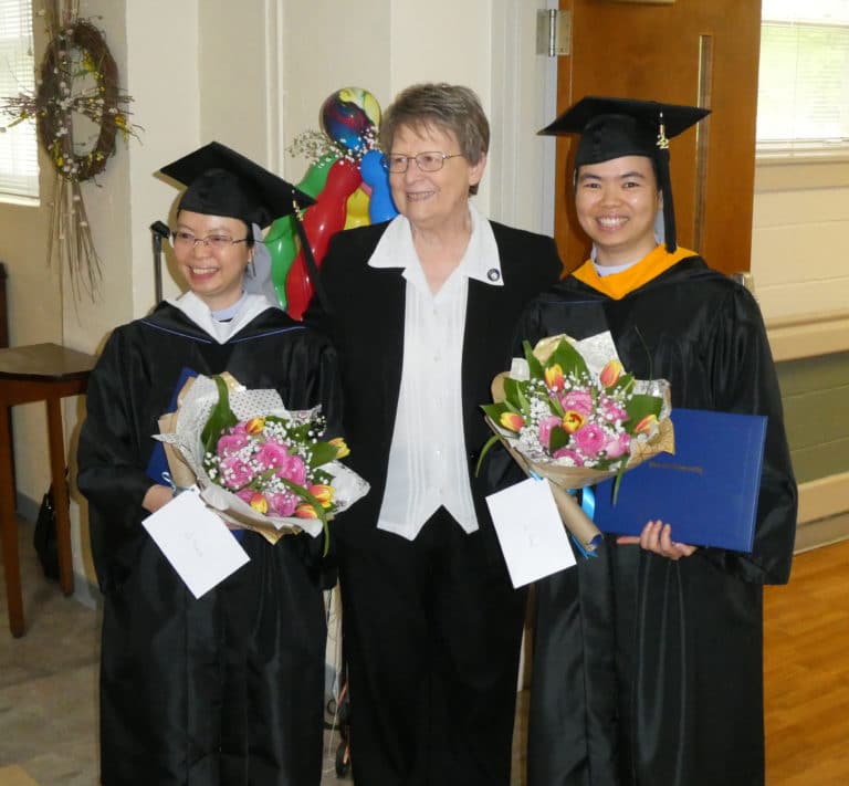 New Brescia graduates Sister Trang Le, left, and Sister Hang Nguyen, are joined by Sister Amelia Stenger, congregational leader of the Ursuline Sisters, as they arrive at the Motherhouse dining room with flowers and their diplomas.