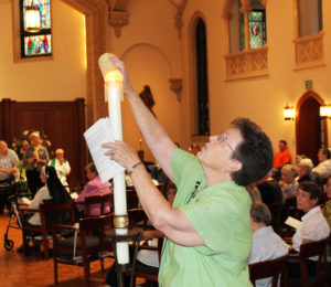 Sister Sharon Sullivan, outgoing congregational leader, lights her candle from the Paschal Candle in the Motherhouse Chapel.