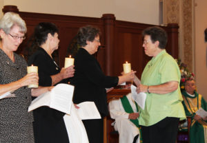 Sister Sharon Sullivan, right, hands her candle to Sister Amelia Stenger.