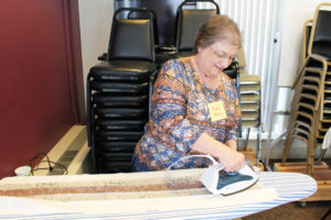 Patty Milroy irons the Double Irish Cross fabric during her first visit to Maple Mount.