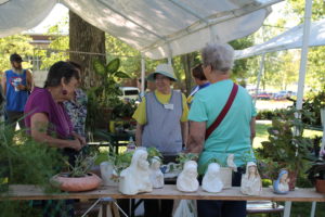 Sister Mary Henning (wearing a hat) smiles as she works in the Plant Sale booth.