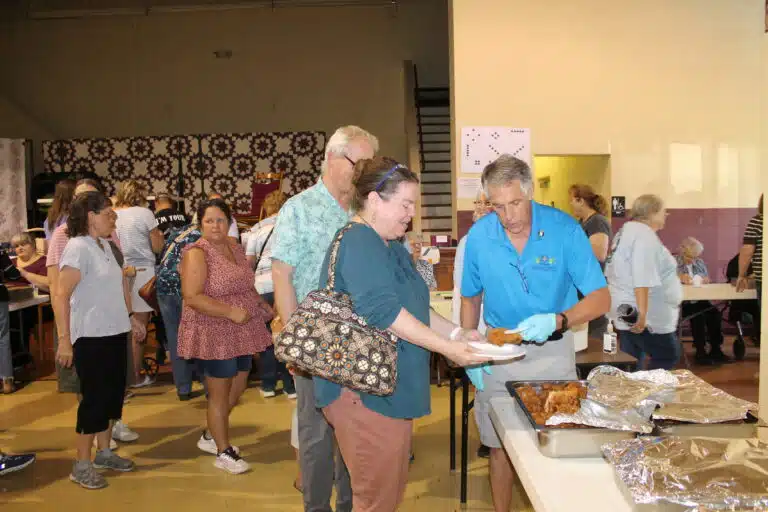 Associate Sam Abbott serves fried chicken to people in the lunch line. Associate Sam Abbott serves fried chicken to people in the lunch line.